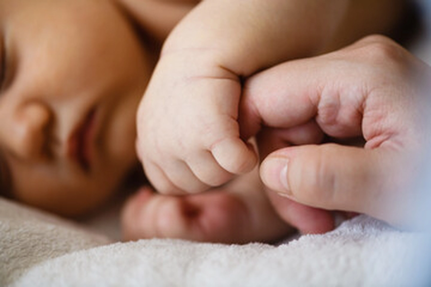 Zeit & Raum für Sie und Ihr Kind - Erzieherin und Heilpädagogin - Ein Baby, das den Finger eines Erwachsenen hält, ist typischerweise die Manifestation des palmaren Greifreflexes, eines unwillkürlichen Instinkts, der eine Schlüsselrolle in der frühen Entwicklung und der Eltern-Kind-Bindung spielt.